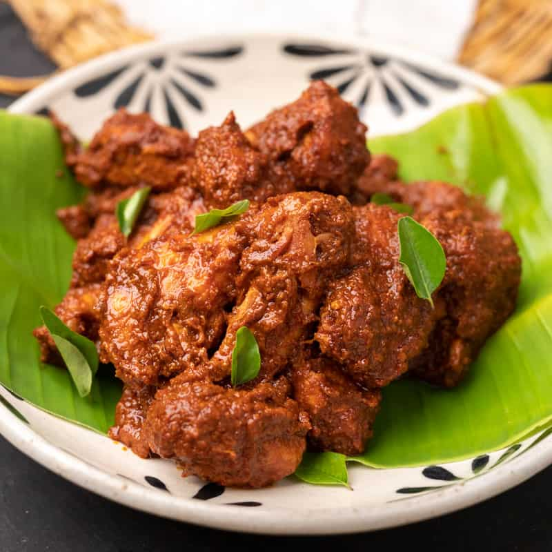 Rich and aromatic Chicken Ghee Roast garnished with curry leaves
